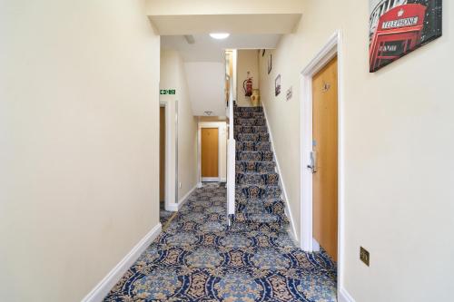 a hallway with stairs with blue and white tiles at Best Western London Ilford Hotel in Ilford