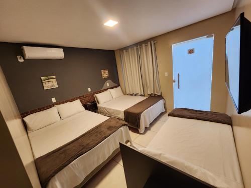 a hotel room with two beds and a television at Pousada King in Vitória da Conquista