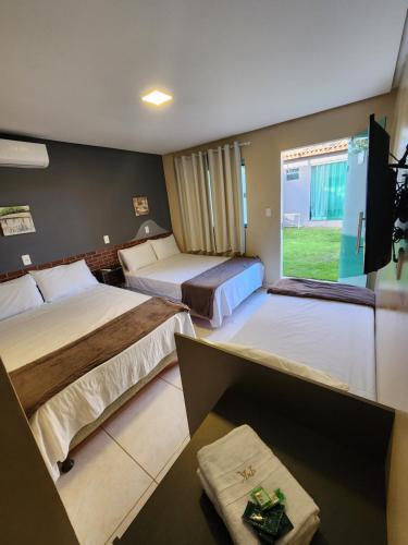a hotel room with two beds and a flat screen tv at Pousada King in Vitória da Conquista