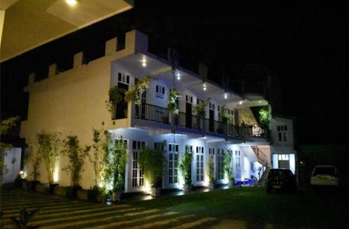 a large white building with a balcony at night at Lodge 52 in Negombo