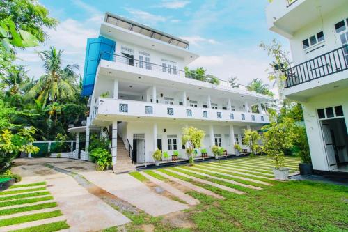 an exterior view of a white building with a yard at Lodge 52 in Negombo