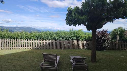 two chairs sitting next to a tree in a yard at Villanath in Bellegarde-sur-Valserine