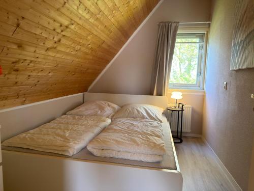 a bed in a room with a wooden ceiling at Vakantiehuis 44 op Recreatiepark De Wielen in Sint Maarten