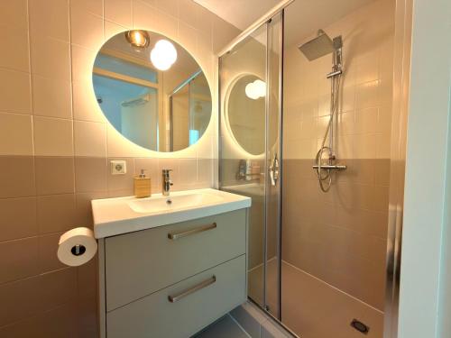 a bathroom with a sink and a shower with a mirror at Vakantiehuis 44 op Recreatiepark De Wielen in Sint Maarten