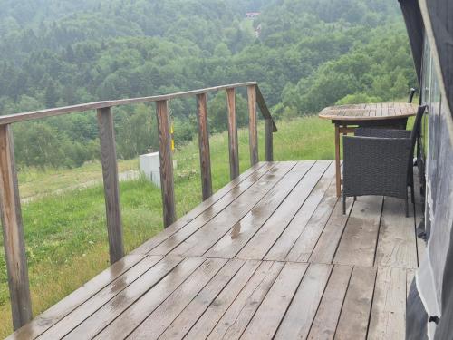 a wooden deck with a table and a chair on it at Camping Obłazek in Piwniczna-Zdrój