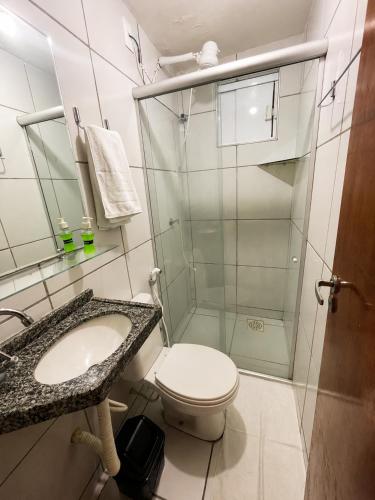 a bathroom with a toilet and a glass shower at Aldenora Flats in Fortaleza