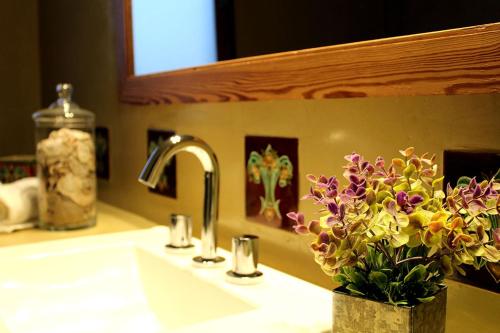 a bathroom sink with a vase of flowers on it at Casa Retama Boutique in Sierra de la Ventana