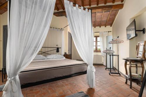 a bedroom with a canopy bed with white curtains at Podere Il Pozzangone by Geco Vacation Rentals in Lucignano