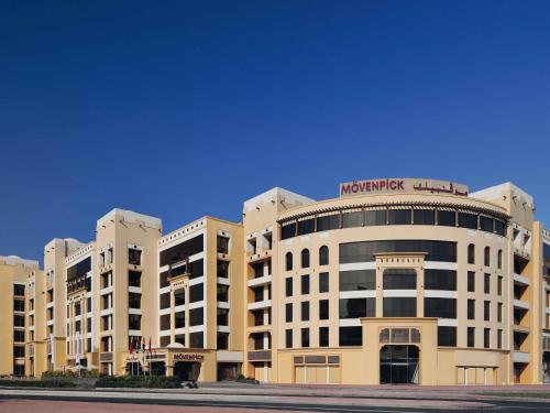 a large white building with a sign on top of it at Mövenpick Hotel Apartments Al Mamzar Dubai in Dubai