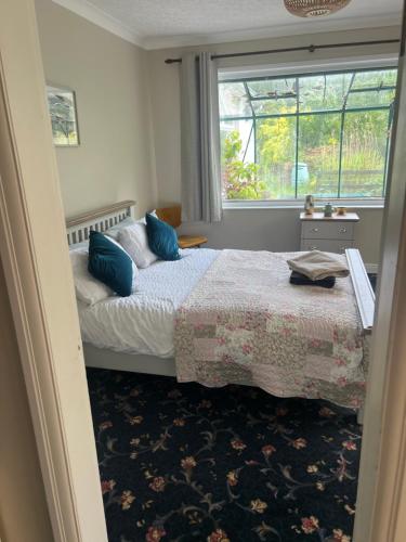 a bedroom with a bed with blue pillows and a window at The Holm in Canonbie