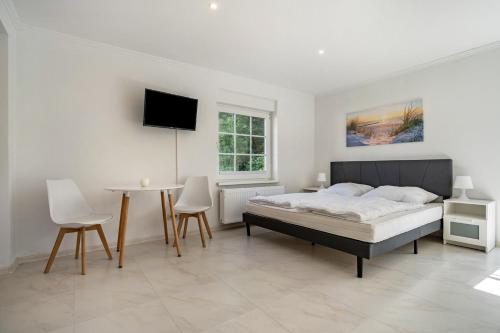 a bedroom with a bed and a table and a tv at Feriendomizil Putbus - Nr. 3b in Putbus