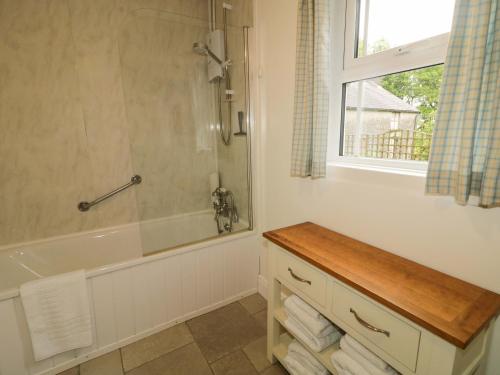 a bathroom with a shower and a tub and a window at Rosslare Cottage in Broughshane