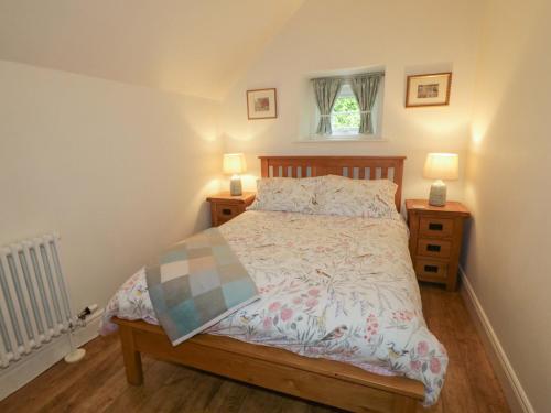 a bedroom with a bed with two night stands and two lamps at Rosslare Cottage in Broughshane