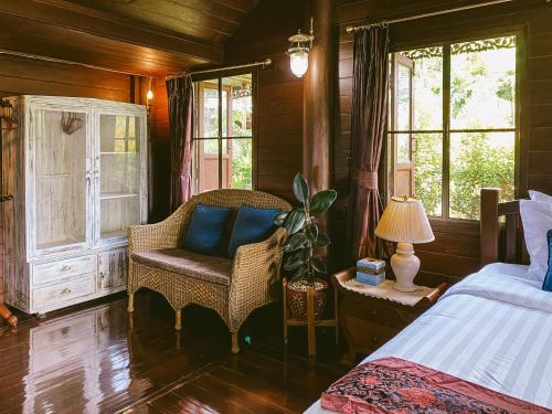 a bedroom with a bed and a chair and windows at Rommai Villa Chiang Rai in Ban Pa Sang (1)