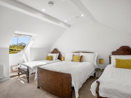 a white room with two beds and a window at Sweet Garden in Ballyconneely