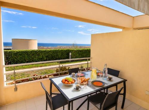 a table with a bowl of fruit on a balcony at Lagune Azur – Séjour cosy vue mer piscine Wi-Fi in Sète