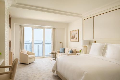 a white bedroom with a large bed and a living room at Four Seasons Hotel Doha in Doha