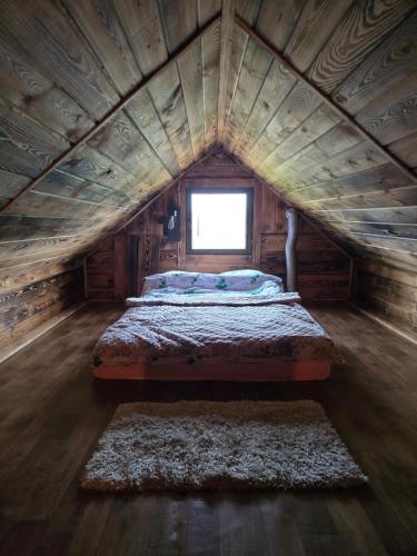 a bed in a wooden room with a window at Słoneczne Łąki in Wólka Soseńska