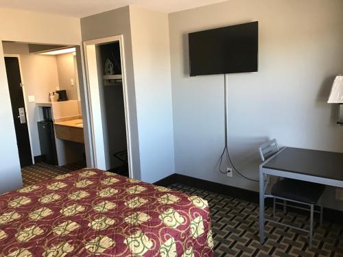 a hotel room with a bed and a desk and a television at Express Inn Weslaco/Mercedes in Weslaco