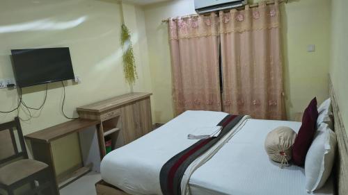 a small bedroom with a bed and a television at Kutumba Home in Bhairāhawā