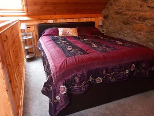 a bedroom with a bed in a log cabin at Yr Hen Efail - Quirky Old Smithy cottage near forest walks, cycling & lakes in Garthbeibio