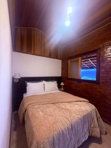 a bedroom with a large bed with a window at Rancho do Ipês in Campos do Jordão