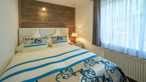 a bedroom with a blue and white bed with a window at Exclusiv Ferienwohnung Maarpanorama in Schalkenmehren