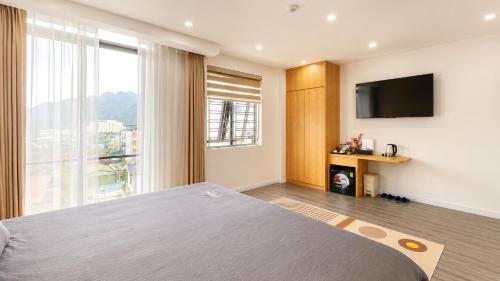 a bedroom with a large bed and a flat screen tv at Gabi Boutique Hotel in Mộc Châu