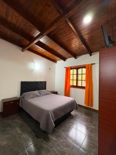 a bedroom with a bed with an orange curtain at Dos Osos in Villa General Belgrano