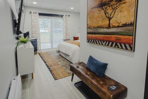 a bedroom with a bed and a bench and a painting at Falkenberg Business Centre and Suites in Botwood