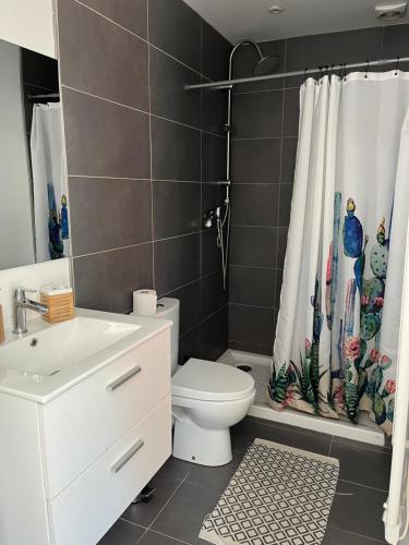 a bathroom with a toilet and a shower curtain at La maison du bonheur in Audenge