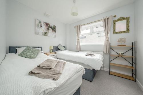 a bedroom with two beds and a window at Stoops Hall - 2 bed first floor apartment in Garstang