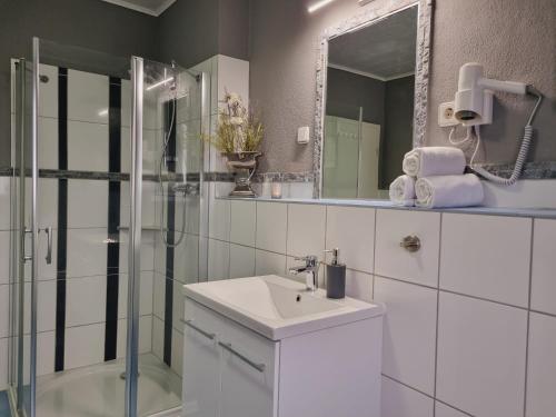 a white bathroom with a sink and a shower at Eifel Dream Casa29 in Burbach