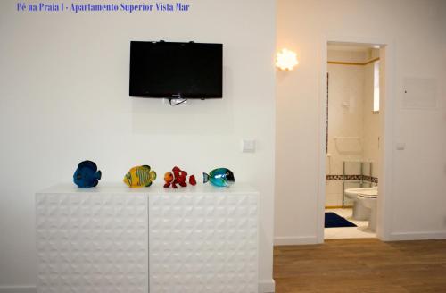 a living room with a tv on a white wall at Pé na Praia in Albufeira