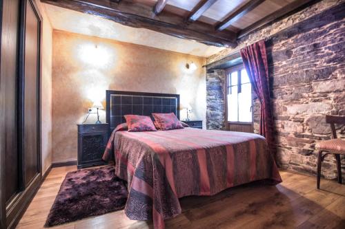 - une chambre avec un lit et un mur en briques dans l'établissement Apartamentos A Casa Nova, à A Pontenova