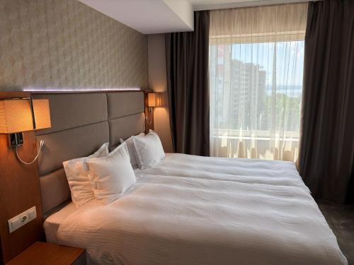 a hotel room with a large bed and a window at Hotel Golden Tulip Varna in Varna City