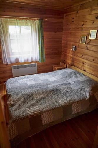 a bedroom with a bed in a log cabin at Ezerzemes in Nirza