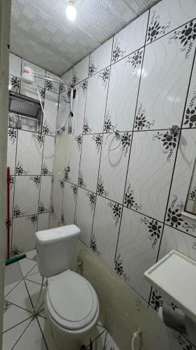 a bathroom with a toilet and a tiled wall at Kitnet aconchegante in Ouro Preto