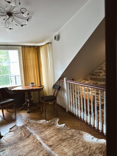a living room with a staircase with a table and a stair case at Karja Castle Apartments in Haapsalu