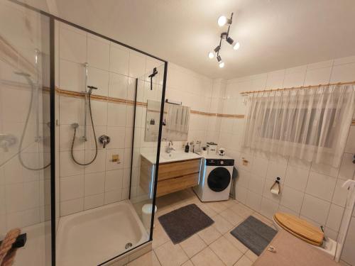 a bathroom with a shower and a sink and a washing machine at Ferienwohnung Look wide in Oberelsbach