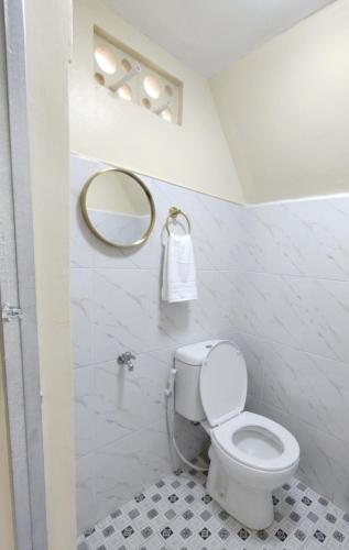 a white bathroom with a toilet and a mirror at Sabda Desa Cabin in Cinyiruan