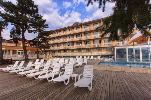 a row of white chairs on a boardwalk next to a hotel at Balneo & SPA Hotel Aura in Velingrad
