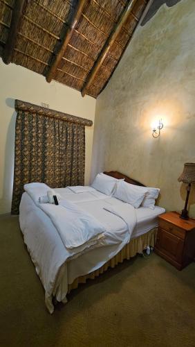 a bedroom with a large bed with white sheets and pillows at Afrika Lodge in Kempton Park