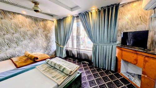 a room with a couch and a tv and curtains at Hotel Five Rivers - 2 Min to Allama Iqbal International Airport, Lahore in Lahore