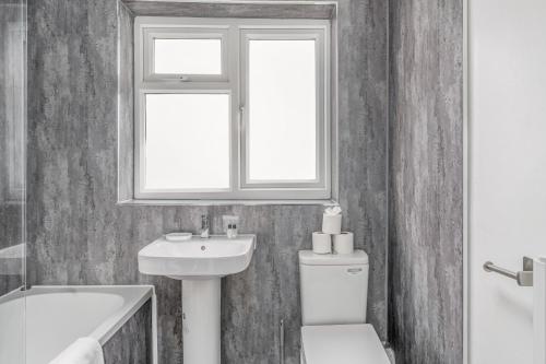 a bathroom with a sink and a toilet and a window at Badger Haven, Apartment 4 in Brackley
