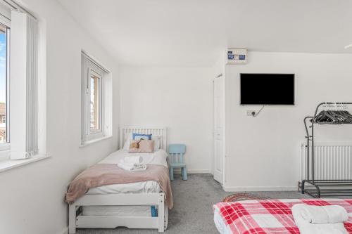 a white room with a bed and a tv at Badger Haven, Apartment 4 in Brackley