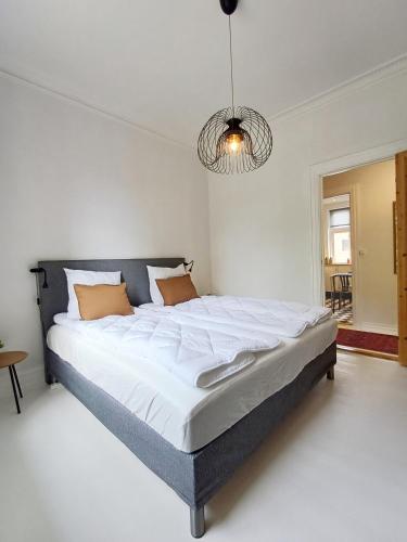 a bedroom with a large bed with white sheets and orange pillows at Exclusive Luxury Apartment with free private parki in Aalborg