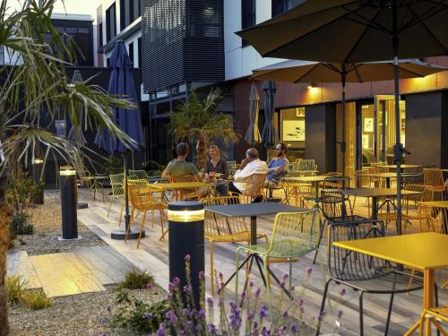 people sitting at tables and chairs at an outdoor restaurant at Aparthotel & Spa Adagio Vannes in Vannes