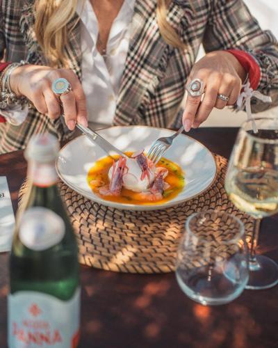 una donna seduta a un tavolo con un piatto di cibo di Borgo Rosso Terra a Gallipoli