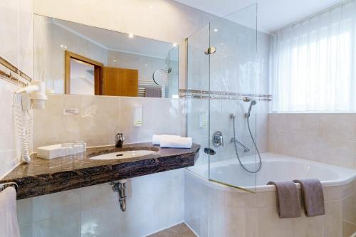 a bathroom with a tub and a sink and a shower at Hotel Gierer in Wasserburg